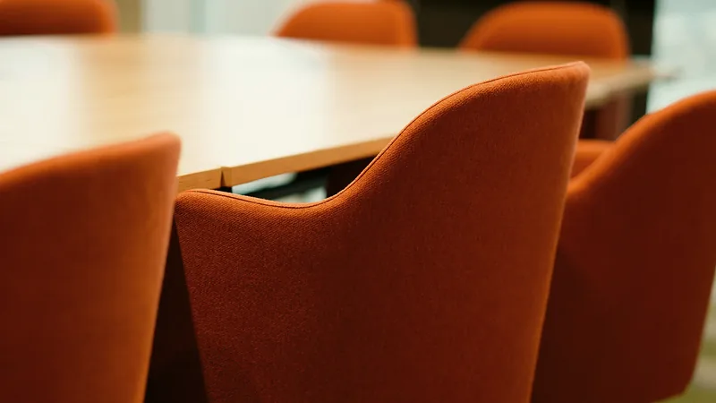 Orangefarbene Polsterstühle an einem hellen Holztisch