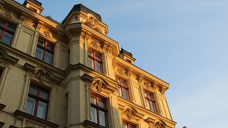 Gelbe Altbaufassade mit Stuck, Ecktürmchen und Holzfenstern im Abendlicht
