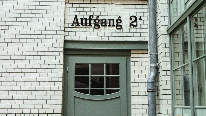 Grüne Tür in einer hellen Klinkerfassade, darüber das Schild „Aufgang 2“
