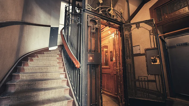 Altes Treppenhaus in Berlin mit geschwungener Treppe und historischem Aufzug